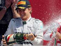 Augen zu und durch: Fernando Alonso (r.) ertrug die Sektdusche von Gewinner Nico Rosberg. Foto: dpa