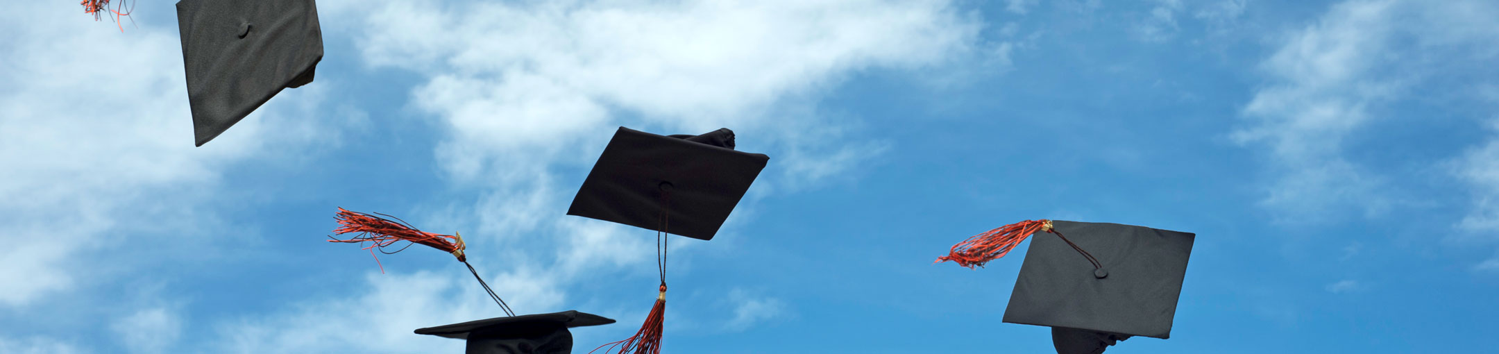 Graduation caps thrown in the air against a blue sky