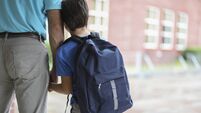 Elementary school boy walks with dad to class.