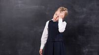 schoolgirl with headache stands at the blackboard