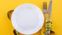 Cutlery and a white plate with measuring tape on a yellow background, the concept of weight loss and diet