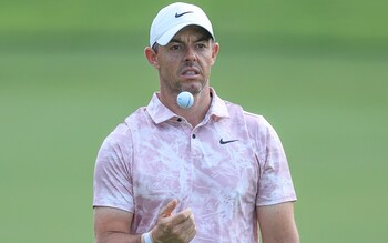 Rory McIlroy tosses his golf ball in the air while looking serious