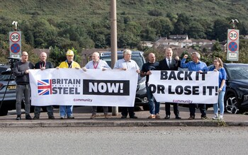 Protesters hold signs outside Tata Steel, is to cut about 2,500 jobs in Port Talbot